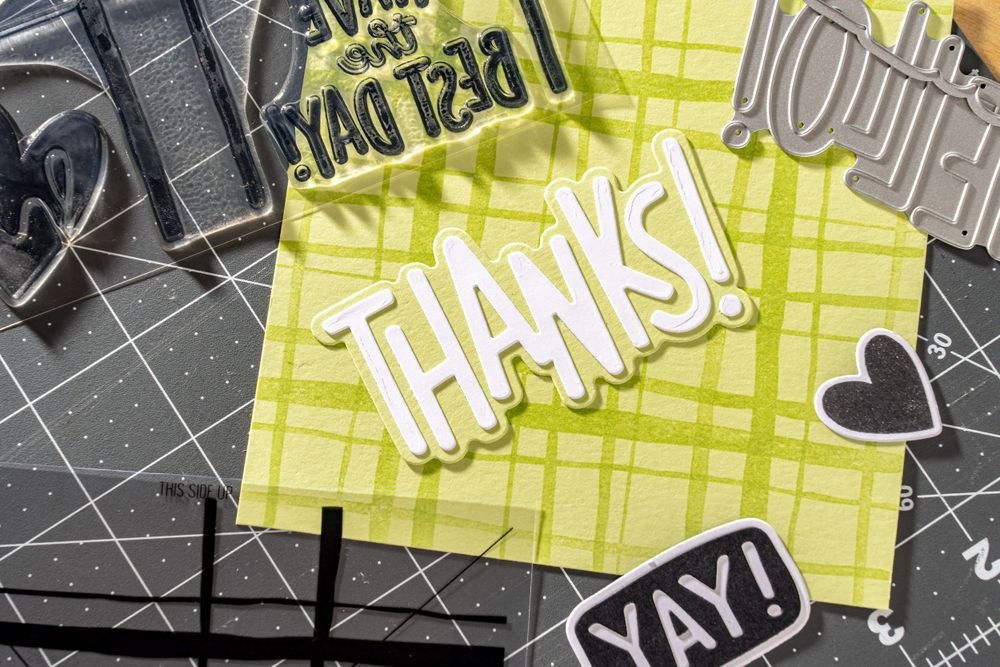 Paper crafting elements spelling 'THANKS' in black, yellow and white tones.