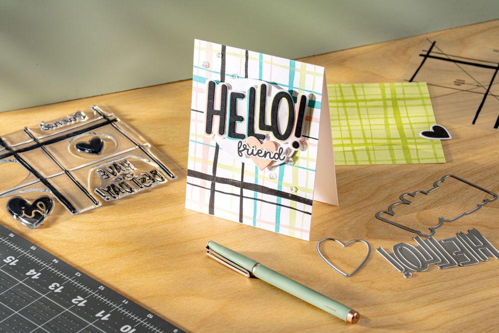Card making supplies including stamps, greeting card, and pen arranged on wooden surface.