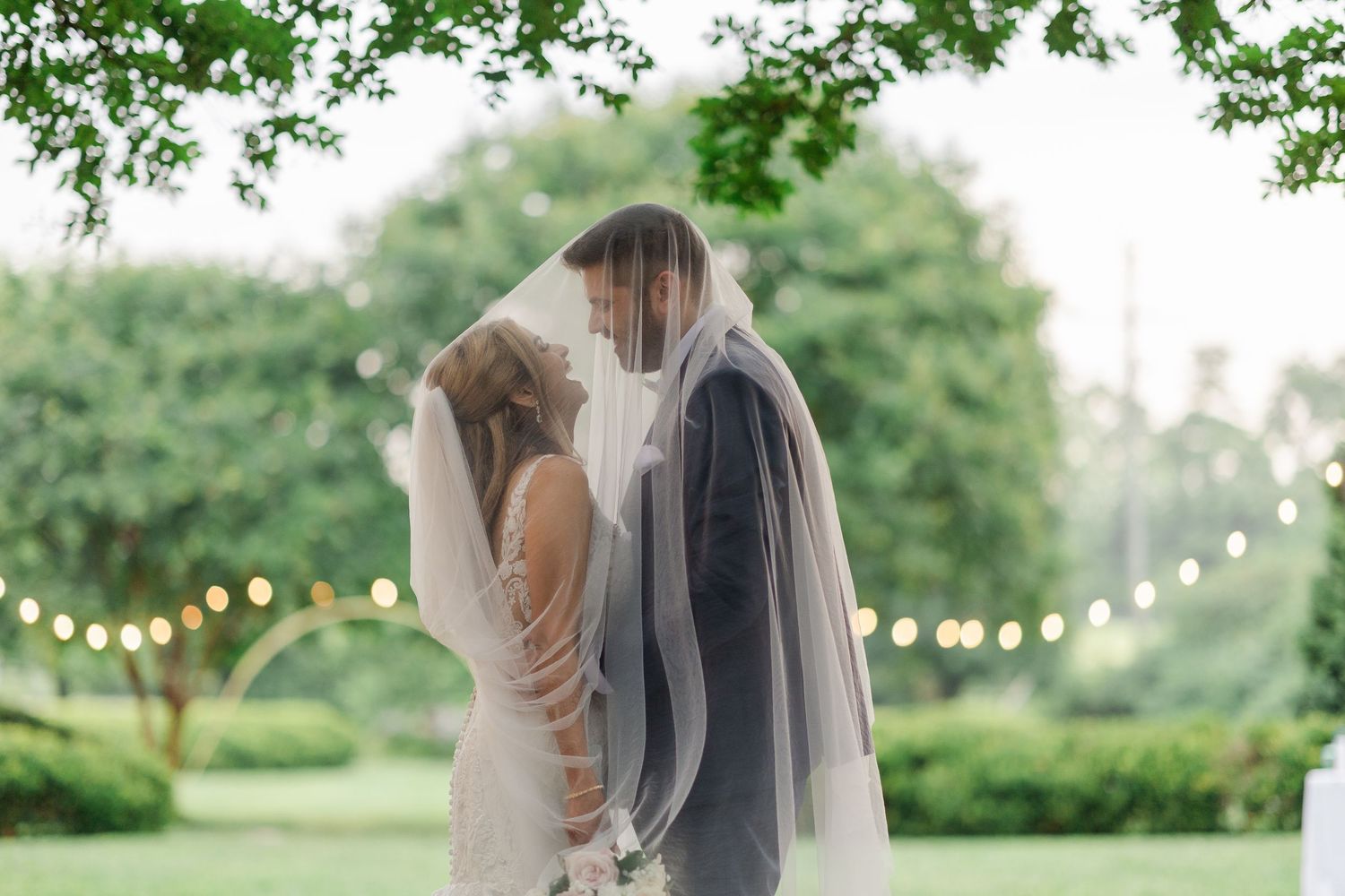 Newlyweds walking together on a wooden dock overlooking a serene lake.