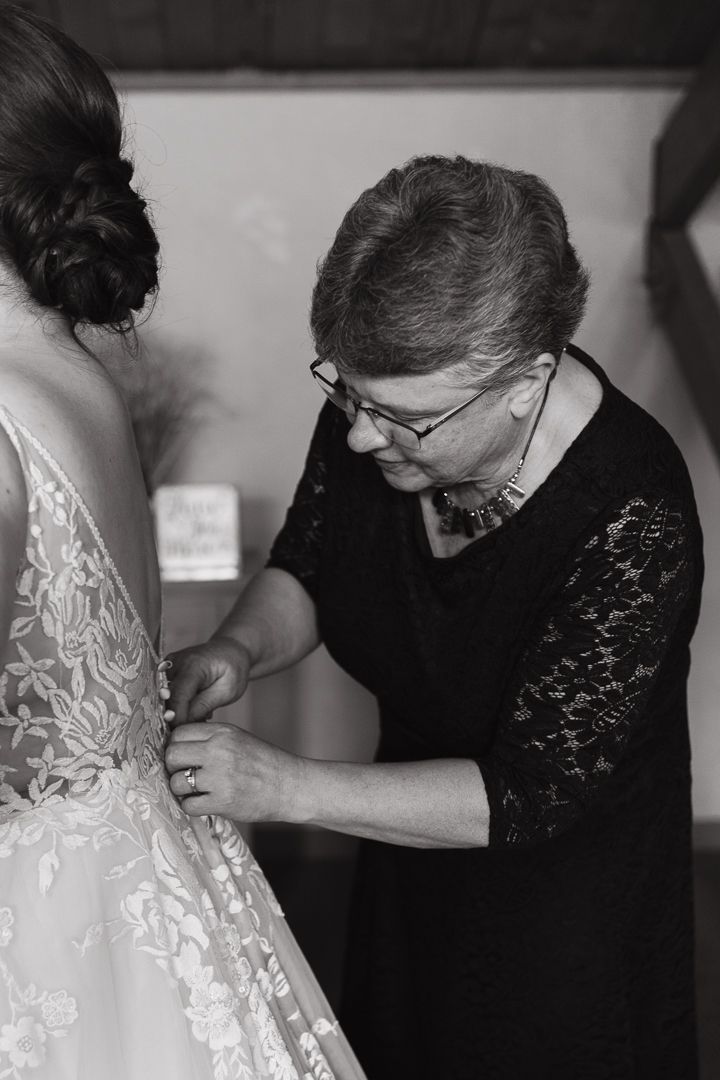 Detail photo of bride putting on dress with mom Duluth Minnesota Wedding