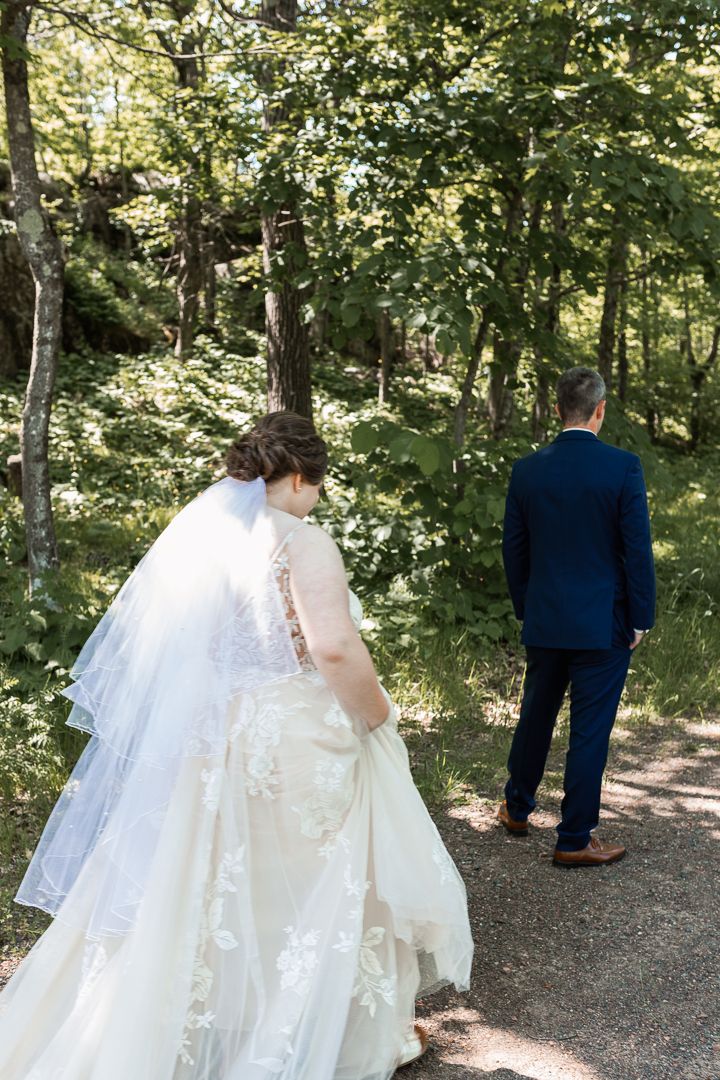 Wedding couple takes first look photos on a wooded trail in natural lighting.