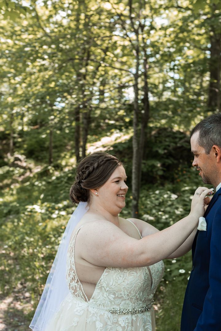 Intimate wedding moment captured in a sunlit forest setting.