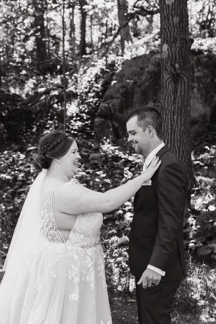 Black and white portrait of a tender wedding moment in a forest setting.