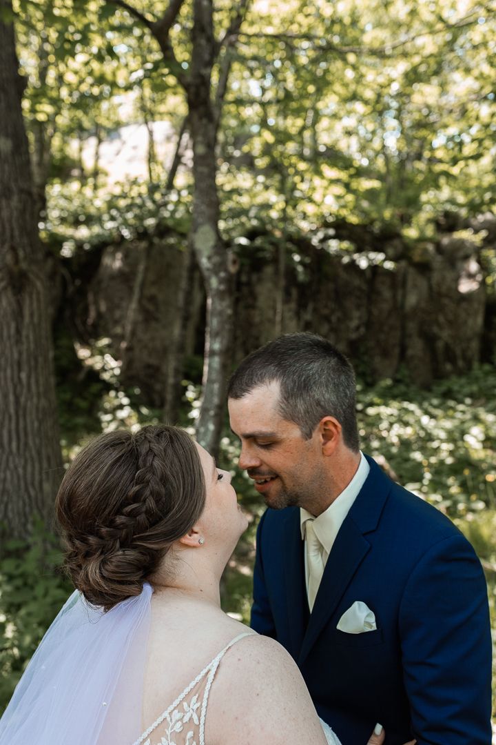 Tender moment between newlyweds in a lush green forest setting.