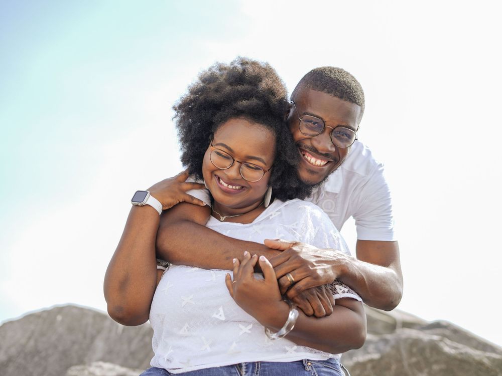 Joyful couple sharing laughter during beach photoshoot on rocky shore.