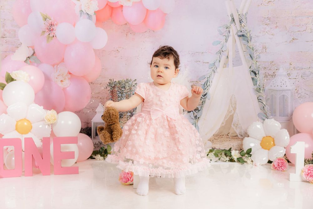 Pink themed first birthday photoshoot with balloons and floral arrangements.