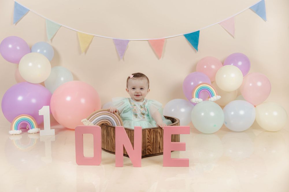 Pastel rainbow themed first birthday setup with colorful balloons and bunting.