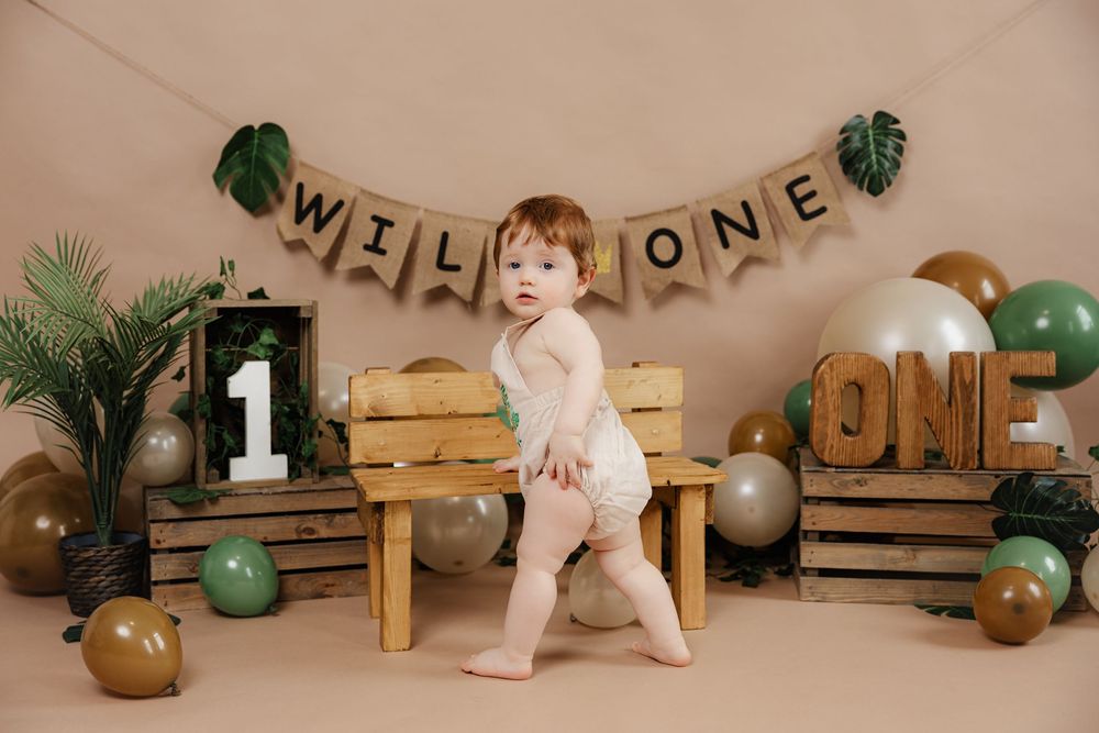 Rustic cake smash photo setup with wood crates, jungle theme decor, balloons, and a minimalist backdrop.