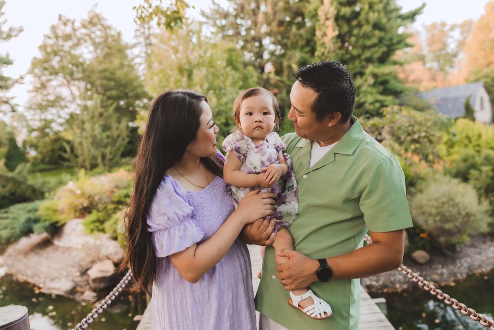 Family sharing a joyful moment together outdoors in a garden setting with lush greenery and decorative lights.