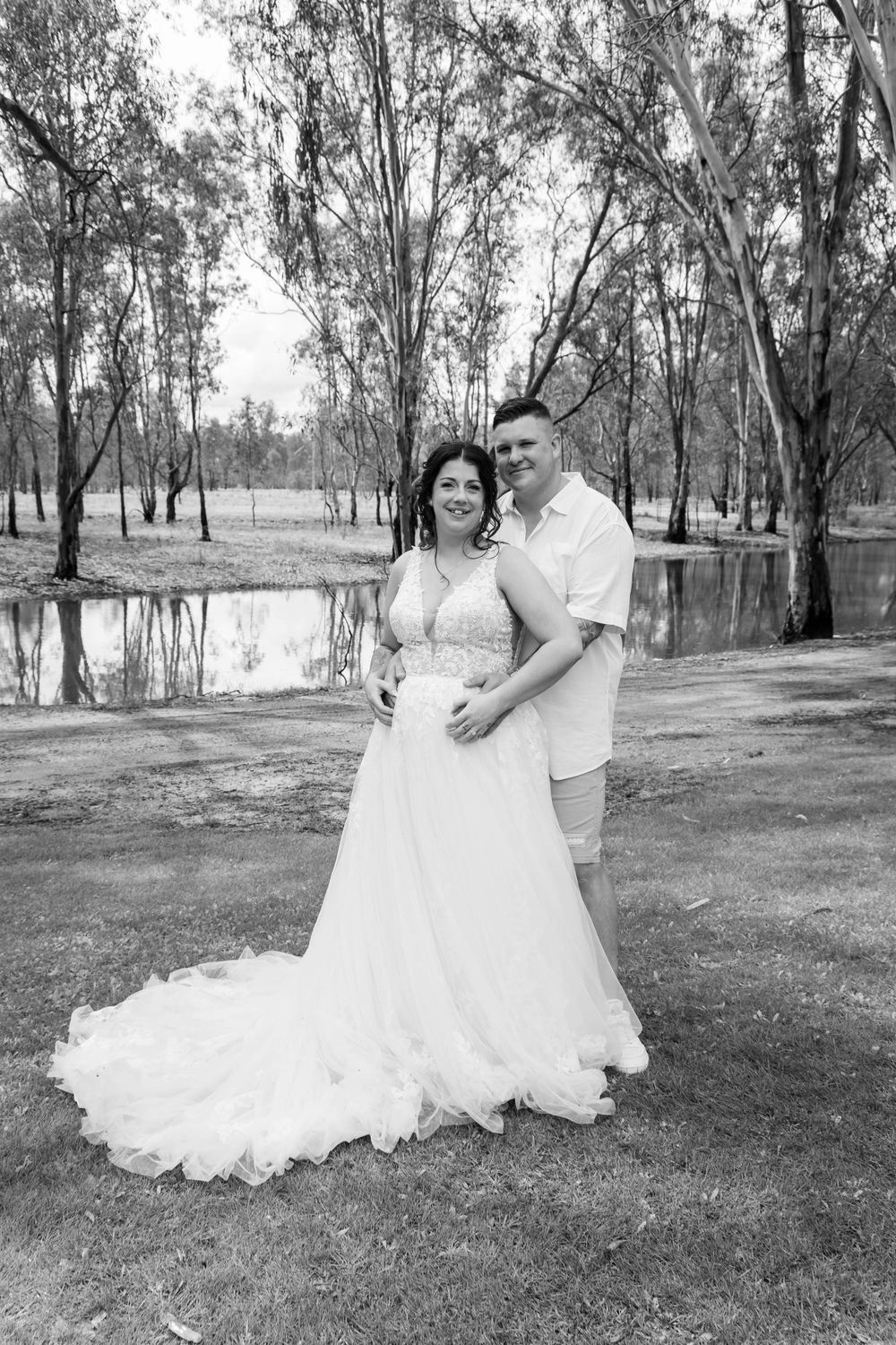 Romantic black and white portrait by pond with gum trees in background.