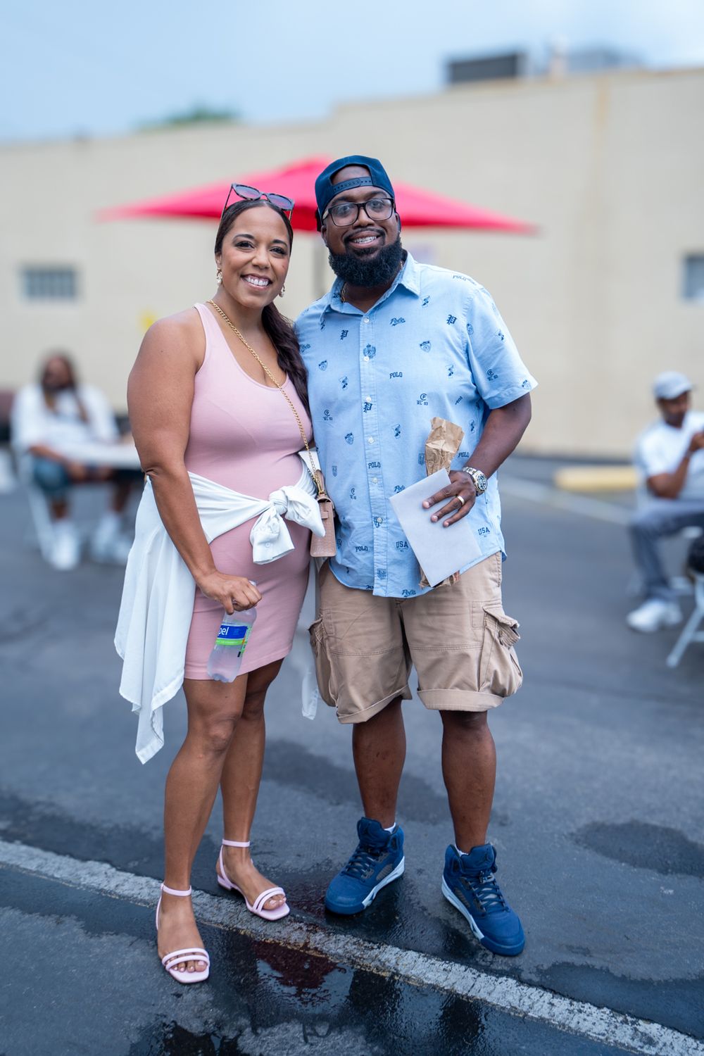 Two people in summer attire smile while standing together outdoors during a casual gathering.