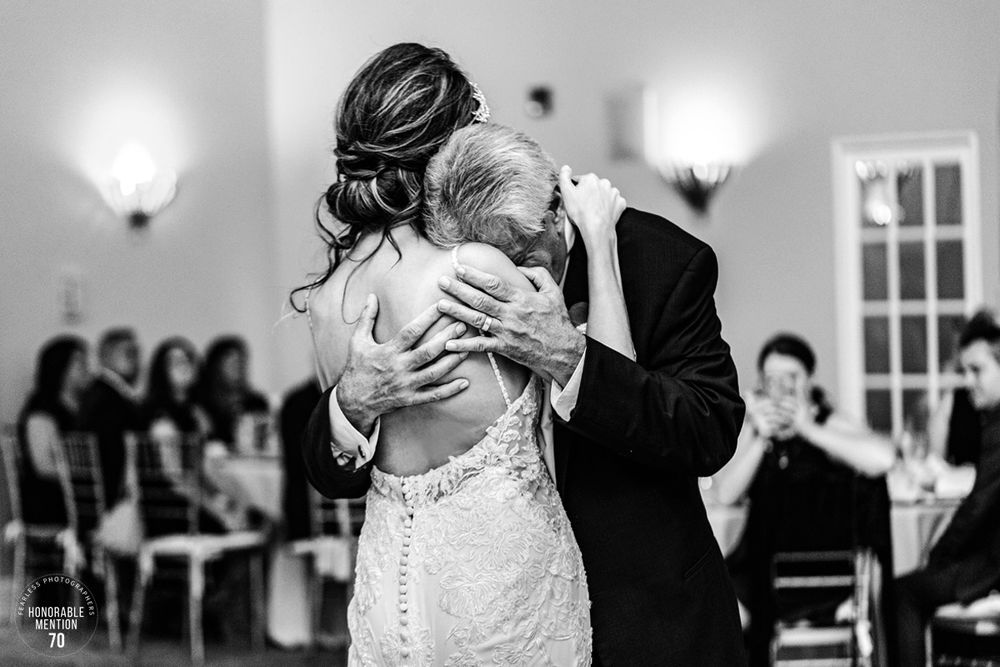 A tender dance moment captured in black and white with guests watching in the background.