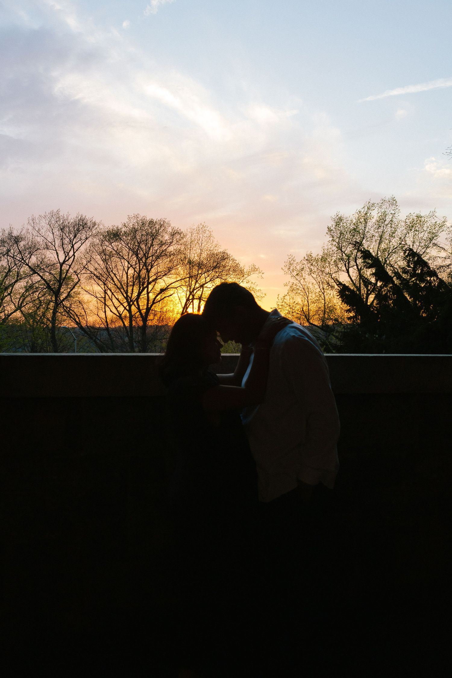 Silhouette of expecting parents with the sun setting behind them, creating a dramatic and artistic maternity portrait.