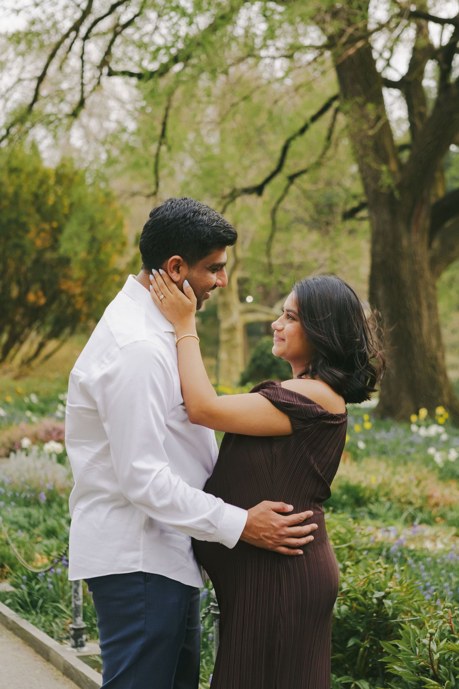 Romantic candid of couple laughing among vibrant florals, capturing intimate maternity moments by NYC maternity photographer Paula Brearley.