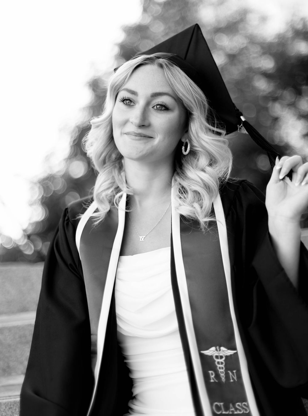 Graduate in cap and gown with medical caduceus stole poses for portrait.