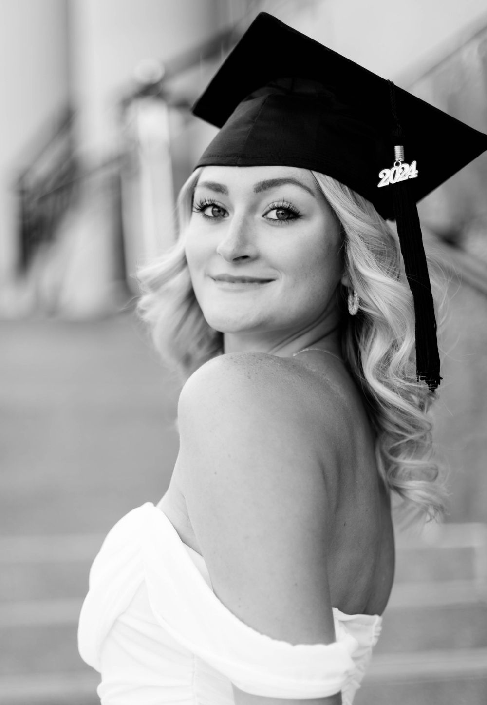 Black and white portrait of graduate in cap and strapless dress.