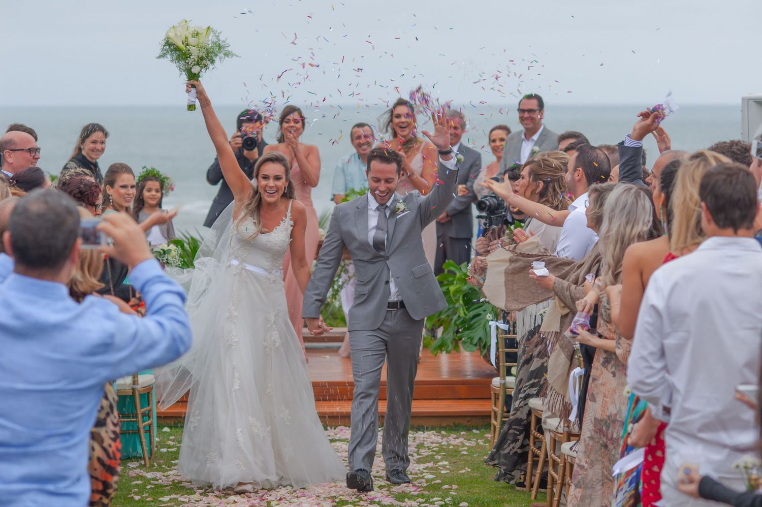 A joyous celebration erupts at an outdoor wedding ceremony as the newlyweds celebrate with guests on a misty day.