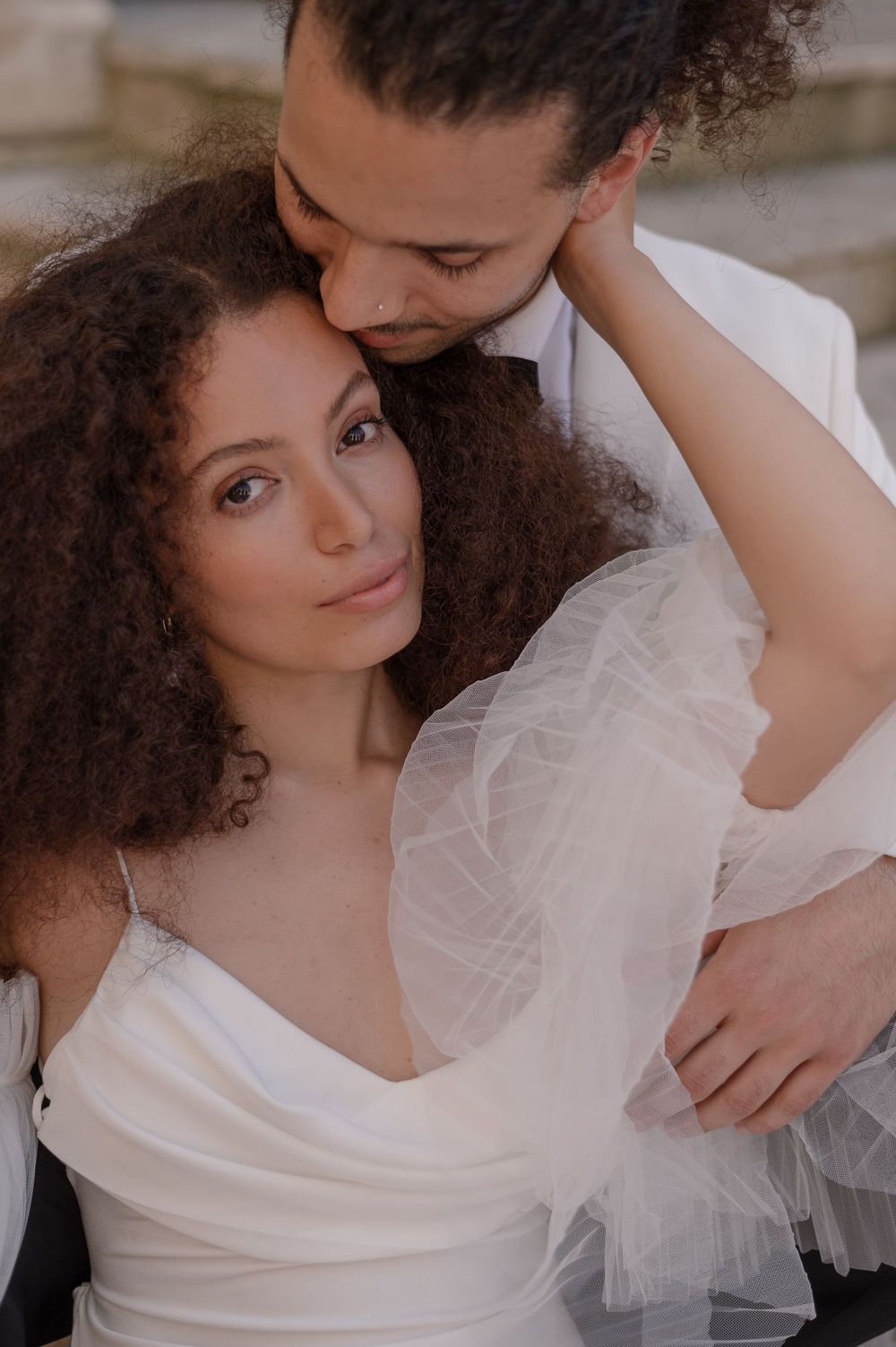 An intimate close-up wedding portrait with soft lighting and elegant white attire.