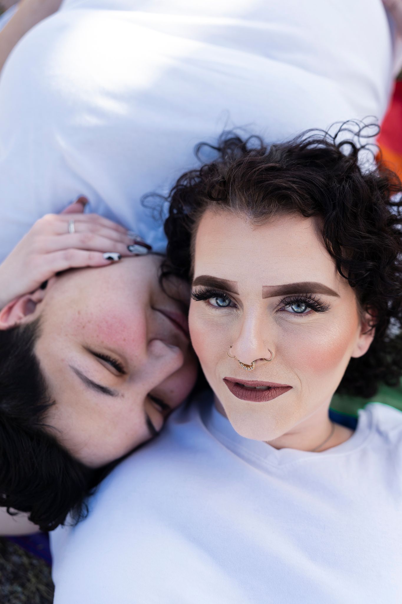 Two individuals in white share an intimate close-up moment while lying down together.
