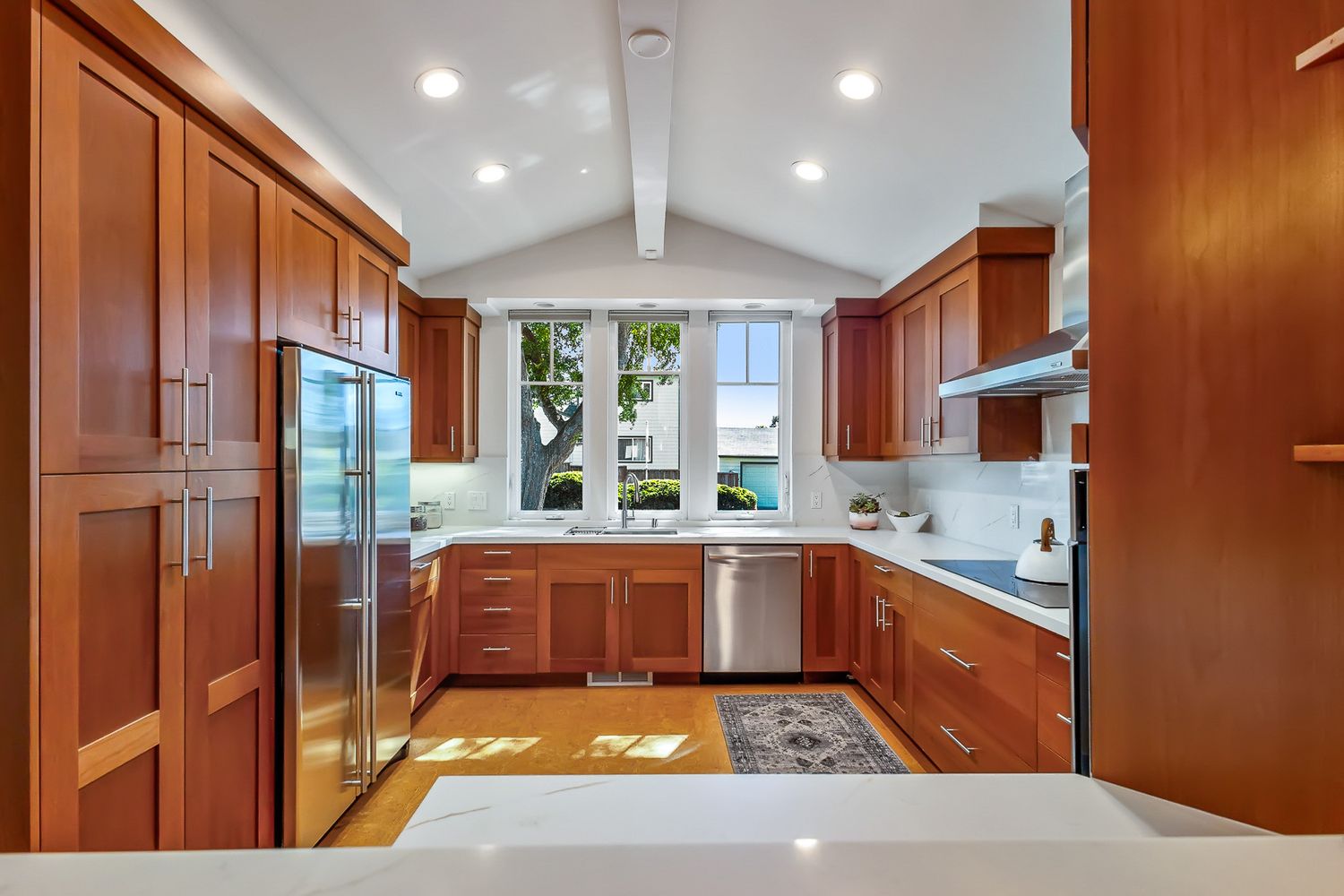 Spacious U-shaped kitchen with cherry wood cabinets, stainless steel appliances, and vaulted ceiling.