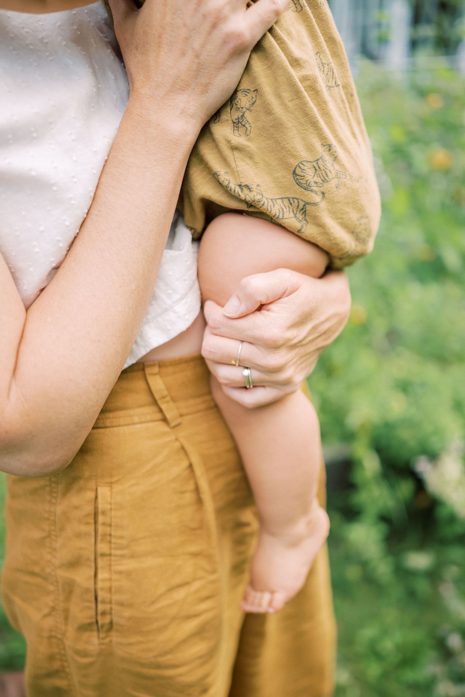 Close-up of baby's legs being held while wearing mustard colored shorts.