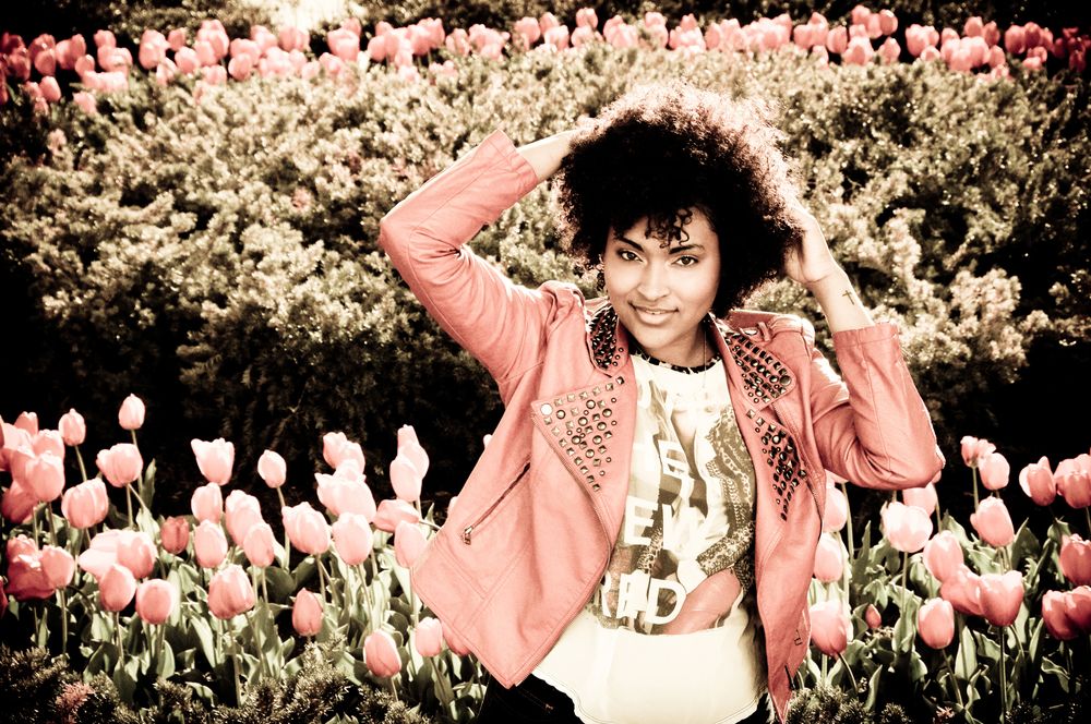 Playful portrait in a pink jacket posing in a garden full of tulips.