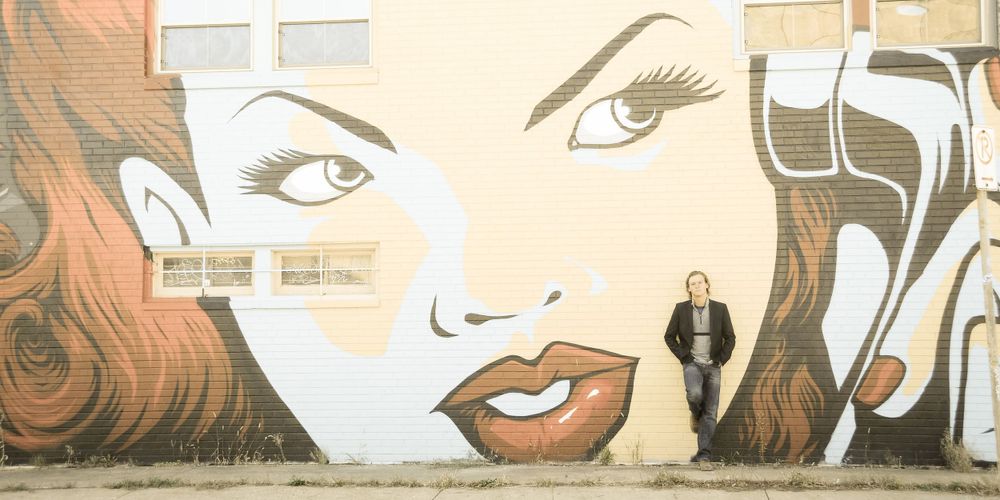 Street art mural of a stylized female face with dramatic eyes and lips.