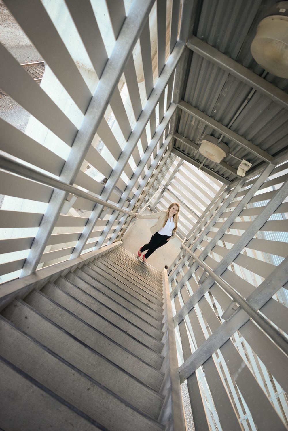 Creative architectural photograph looking down geometric stairwell with person positioned at center.