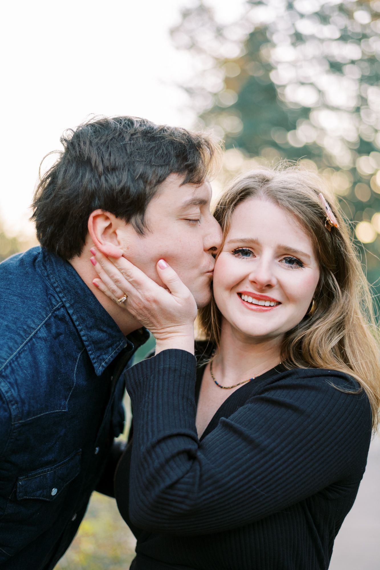 A romantic couple shares an intimate moment outdoors with golden bokeh in the background.