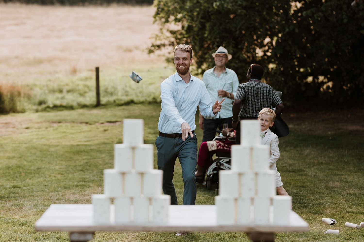 Wedding guests play games on lawn during drinks reception at Lyde Court