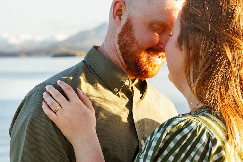 A romantic sunset moment between a couple embracing outdoors with golden light illuminating their closeness.
