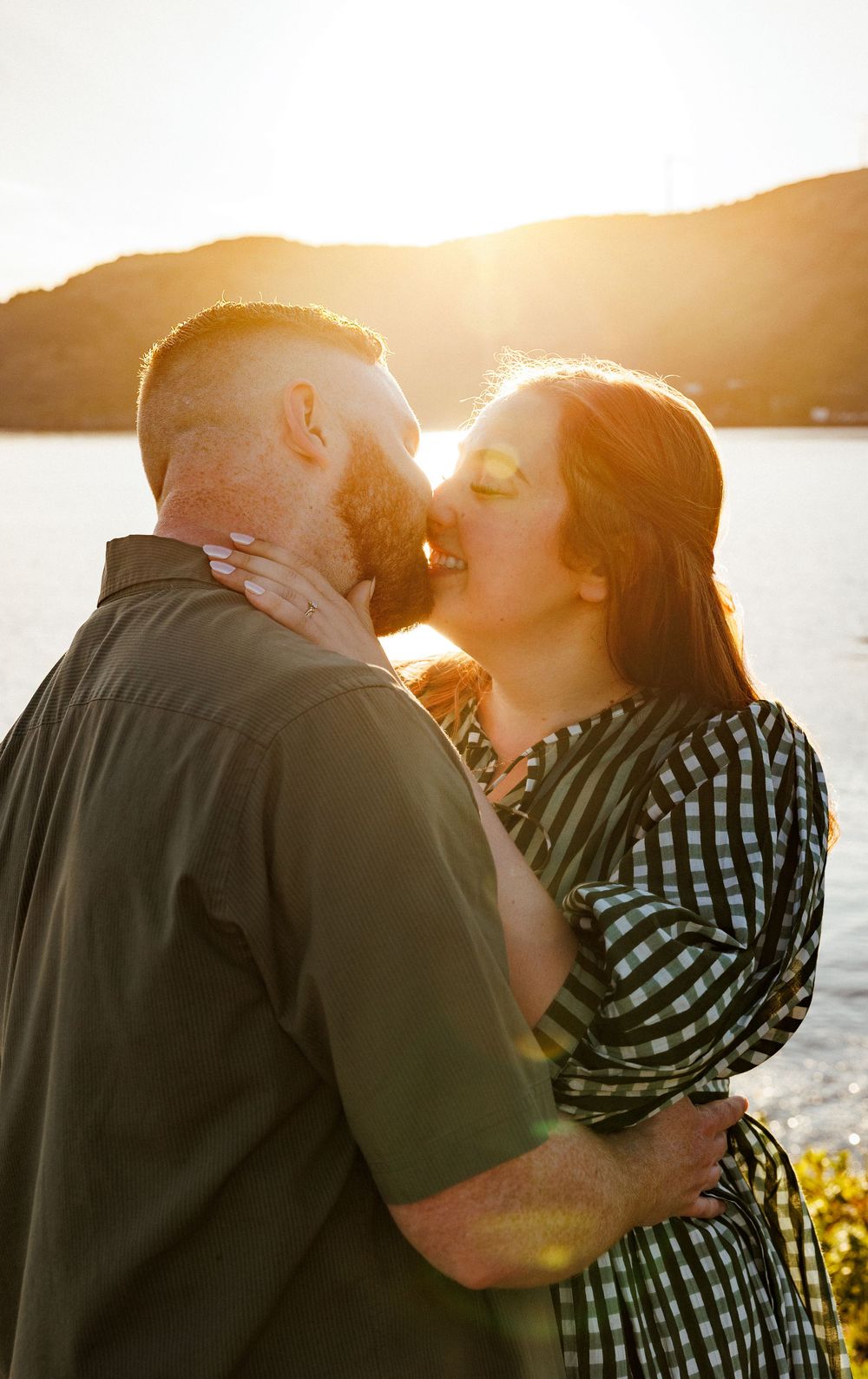A romantic sunset photo session with a couple sharing intimate moments by the water's edge as golden light glows behind them.
