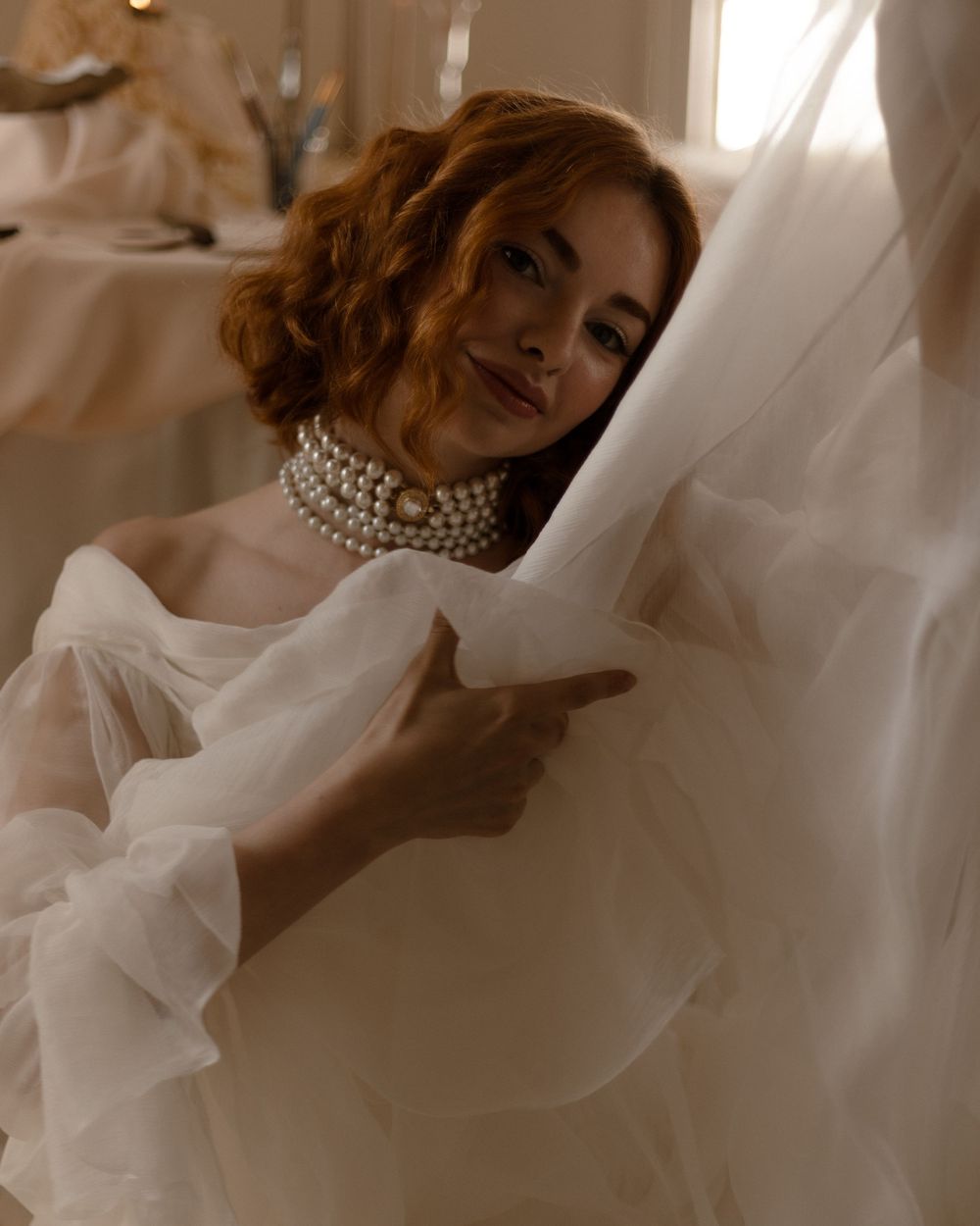 A sepia-toned bridal portrait showing delicate moments with flowing white fabric in a romantic style.