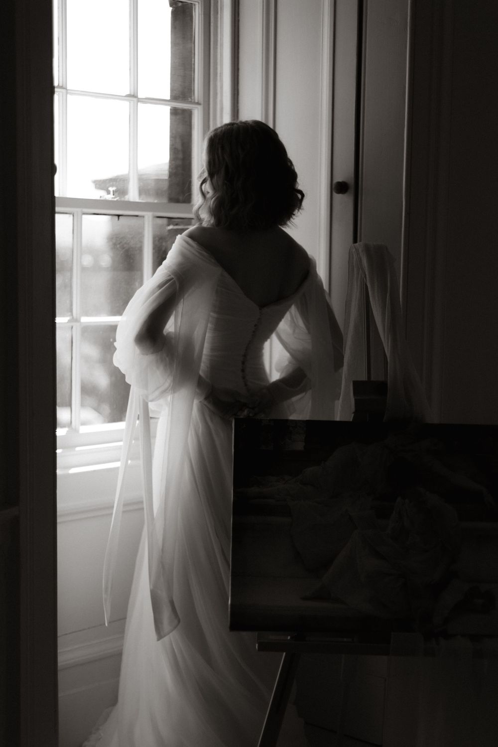 Silhouetted figures in white dresses dance by windows in a romantic and dreamy black and white photo sequence.