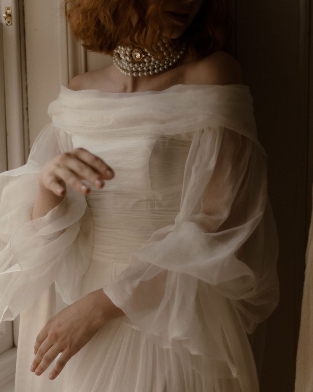 Closeup details of a romantic white wedding dress with delicate tulle fabric and pleated layers creating elegant texture.