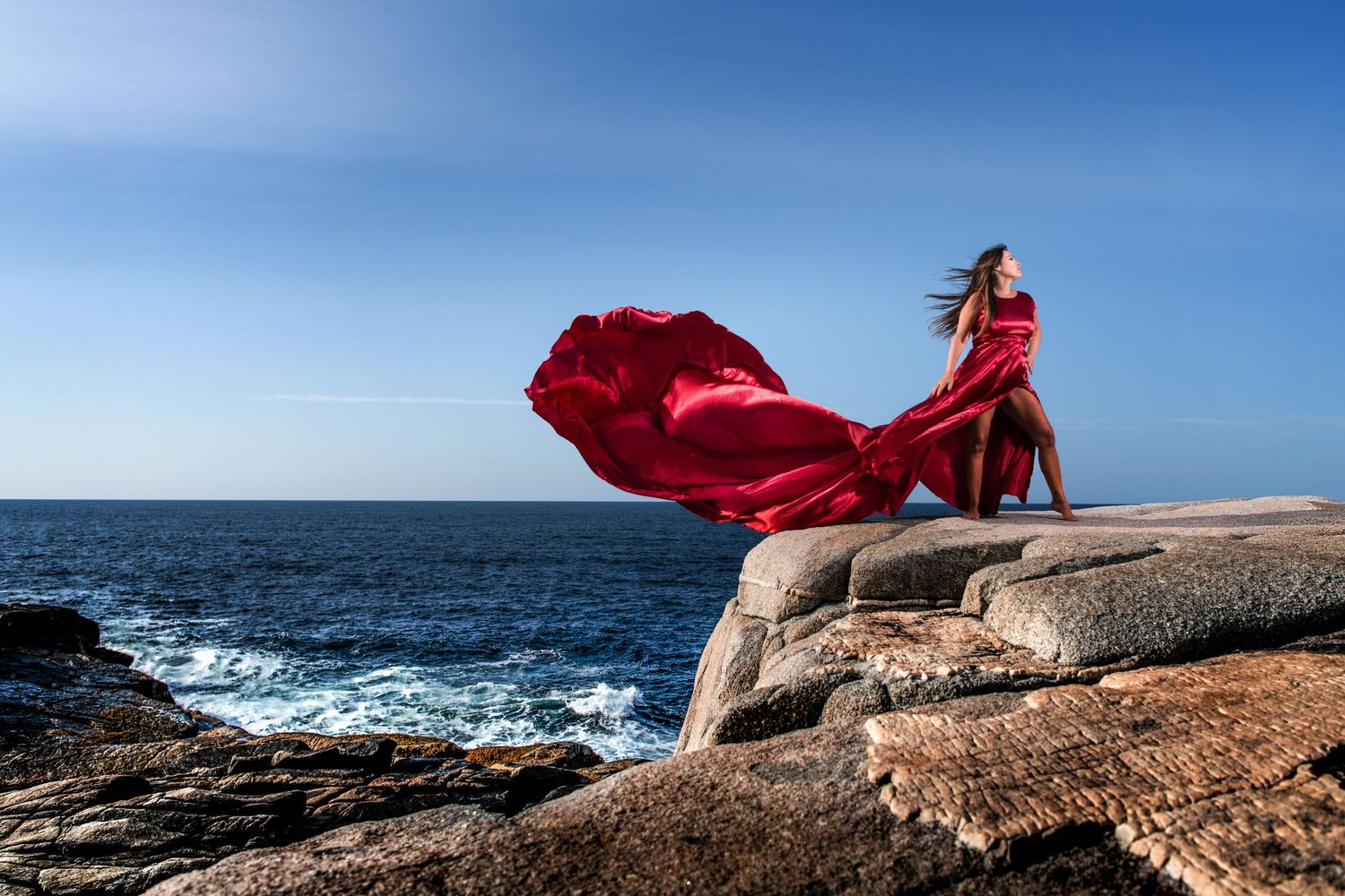 Stunning Flying Dress Photo Shoot Peggy's Cove, Nova Scotia showing the waves crashing below.
