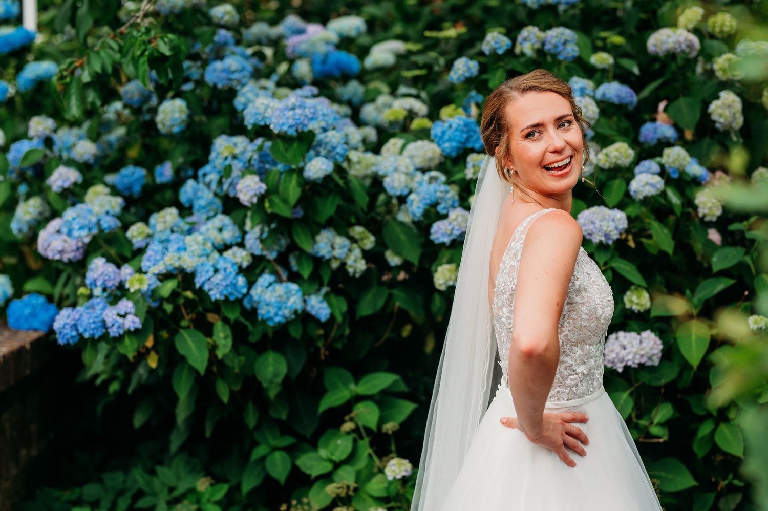 A candid moment beside blooming blue hydrangea bushes in a lush garden setting.