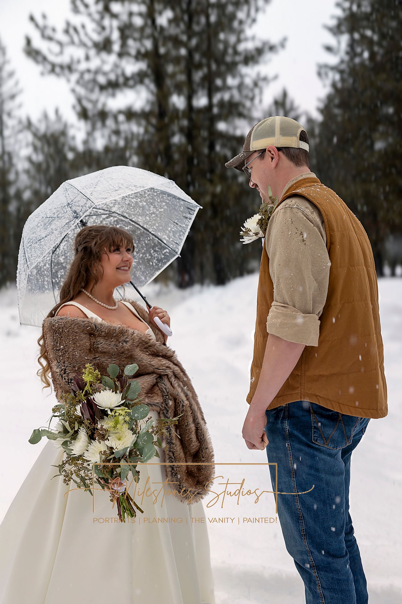bride holding clear umbrella grinning at groom in the snow