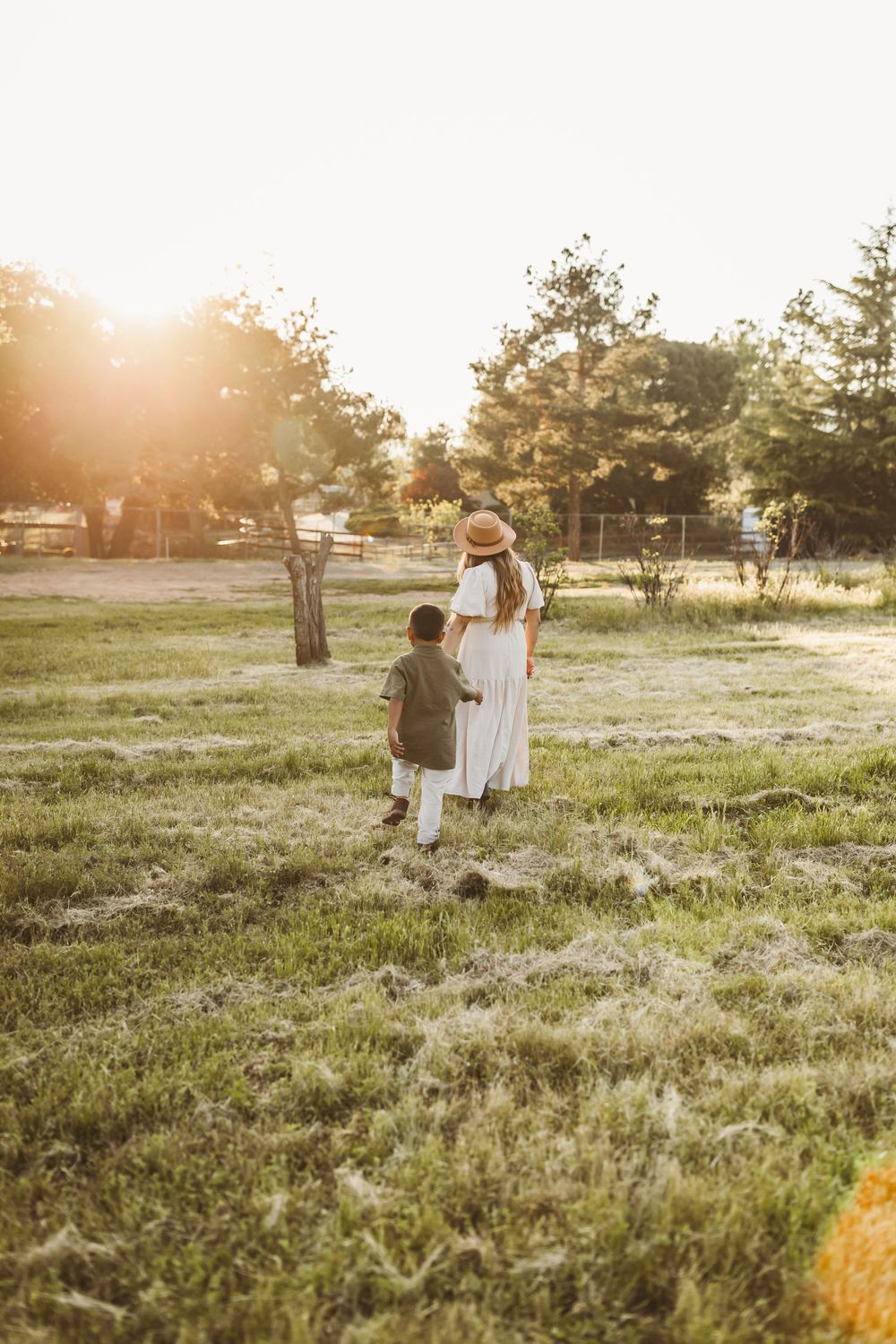 Two figures stand together in a sunlit meadow during golden hour.
