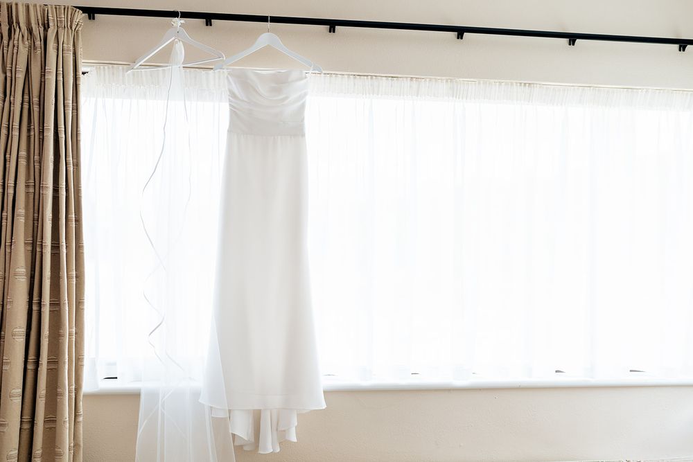Modern minimalist bedroom interior with white walls, sheer curtains and black curtain rod mounted near ceiling.