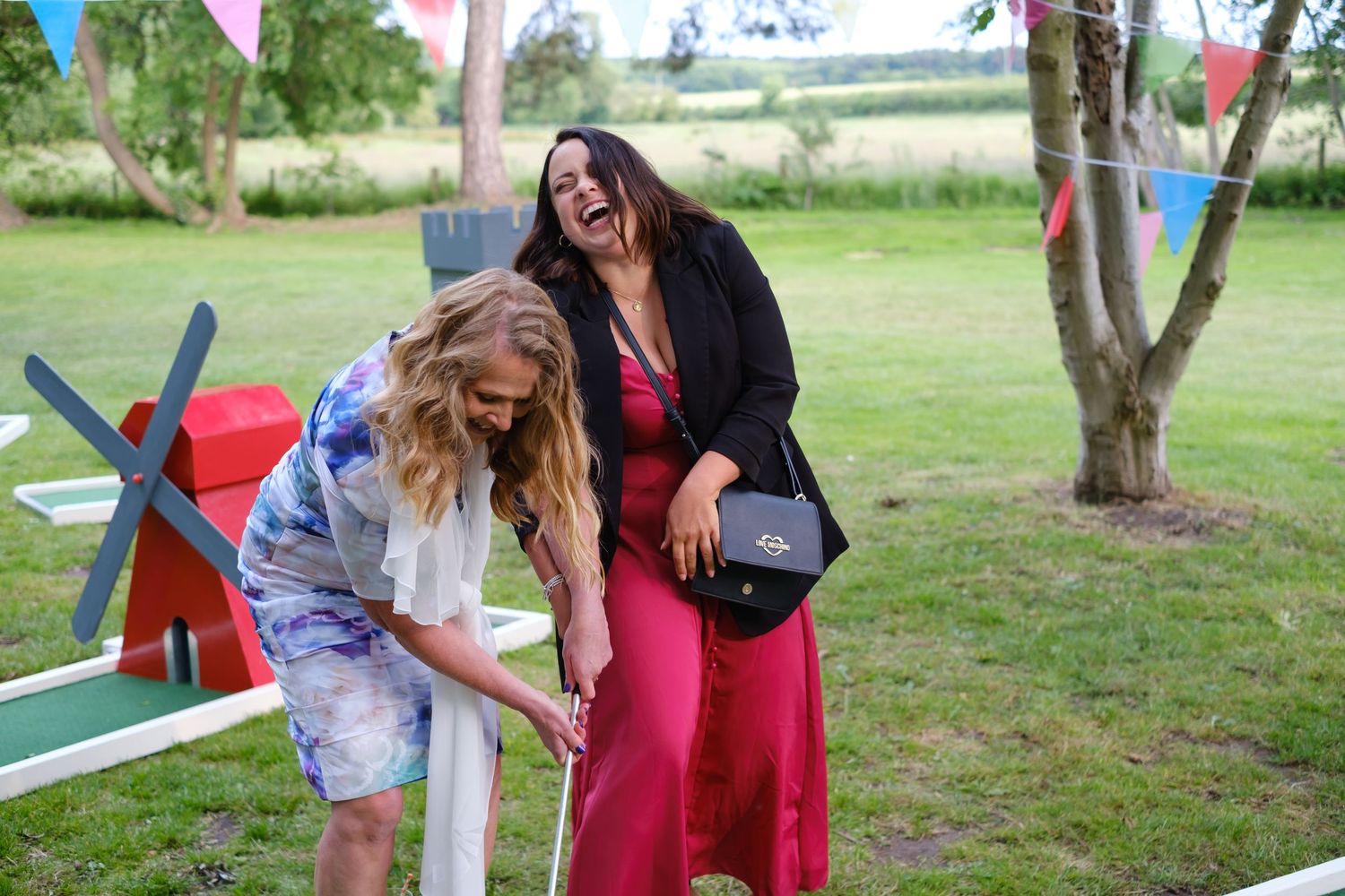 Guests laughing whilst trying to play mini golf.