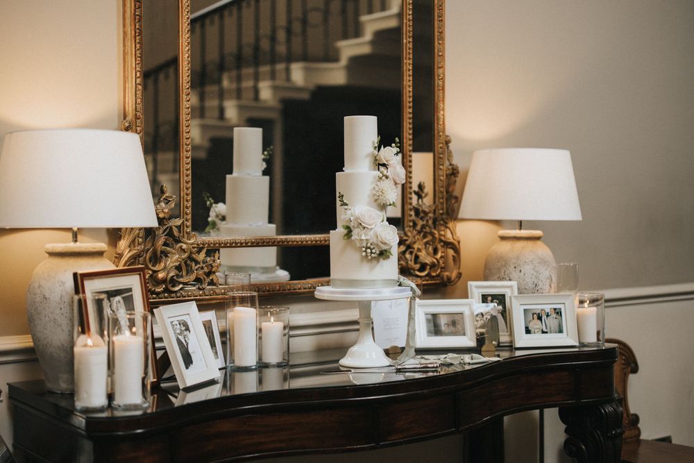 Elegant console table display with framed photos, white table lamps, and ornate gold mirror at Saltmarshe Hall - by Grimsby photographers.