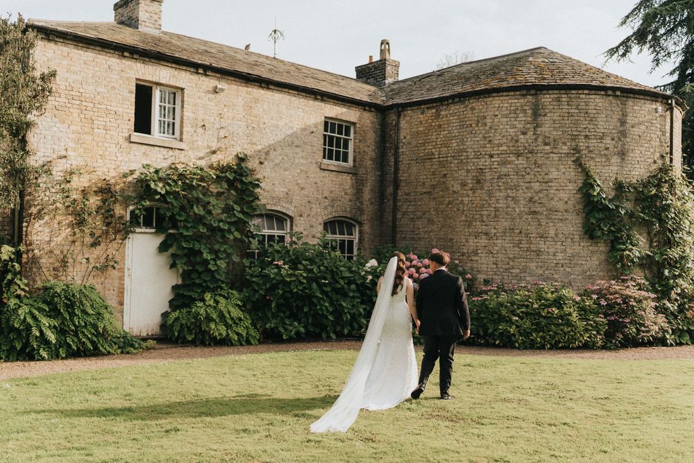 A couple walks together on a pristine lawn outside Saltmarshe Hall - taken by Grimsby photographer.