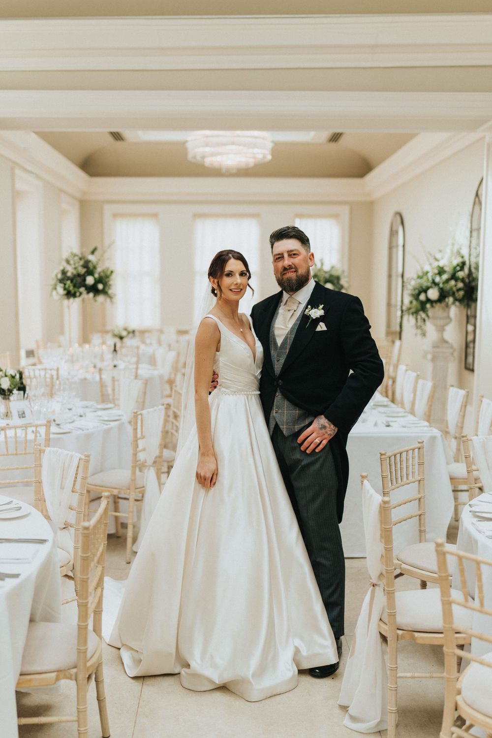 A wedding couple poses in an elegant white reception hall with chiavari chairs at Saltmarshe Hall - taken by Grimsby photographer.