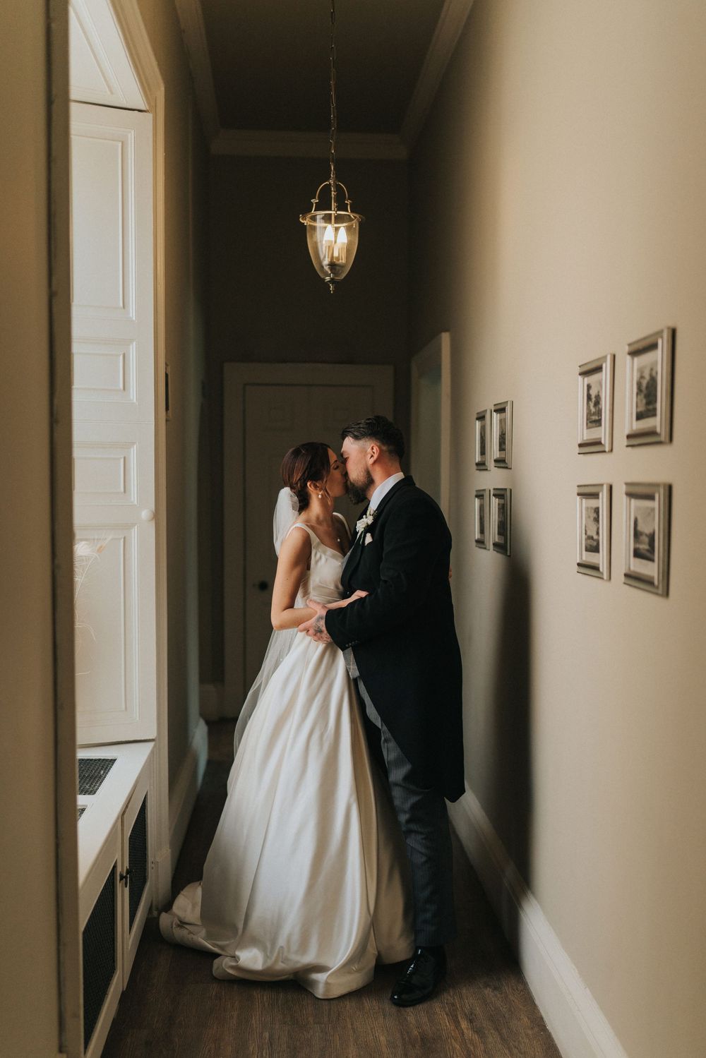 A couple shares an intimate wedding moment in a dimly lit hallway at Saltmarshe Hall - taken by Grimsby photographer.