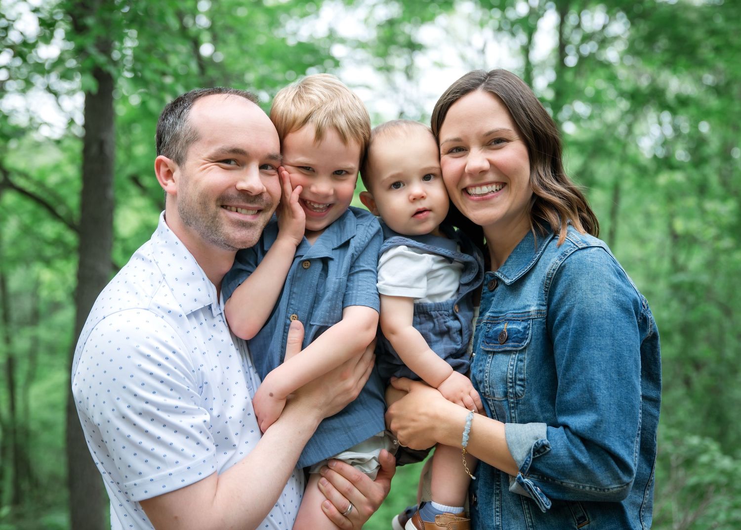 Loving family enjoys tender moments together outdoors against a green forest background.