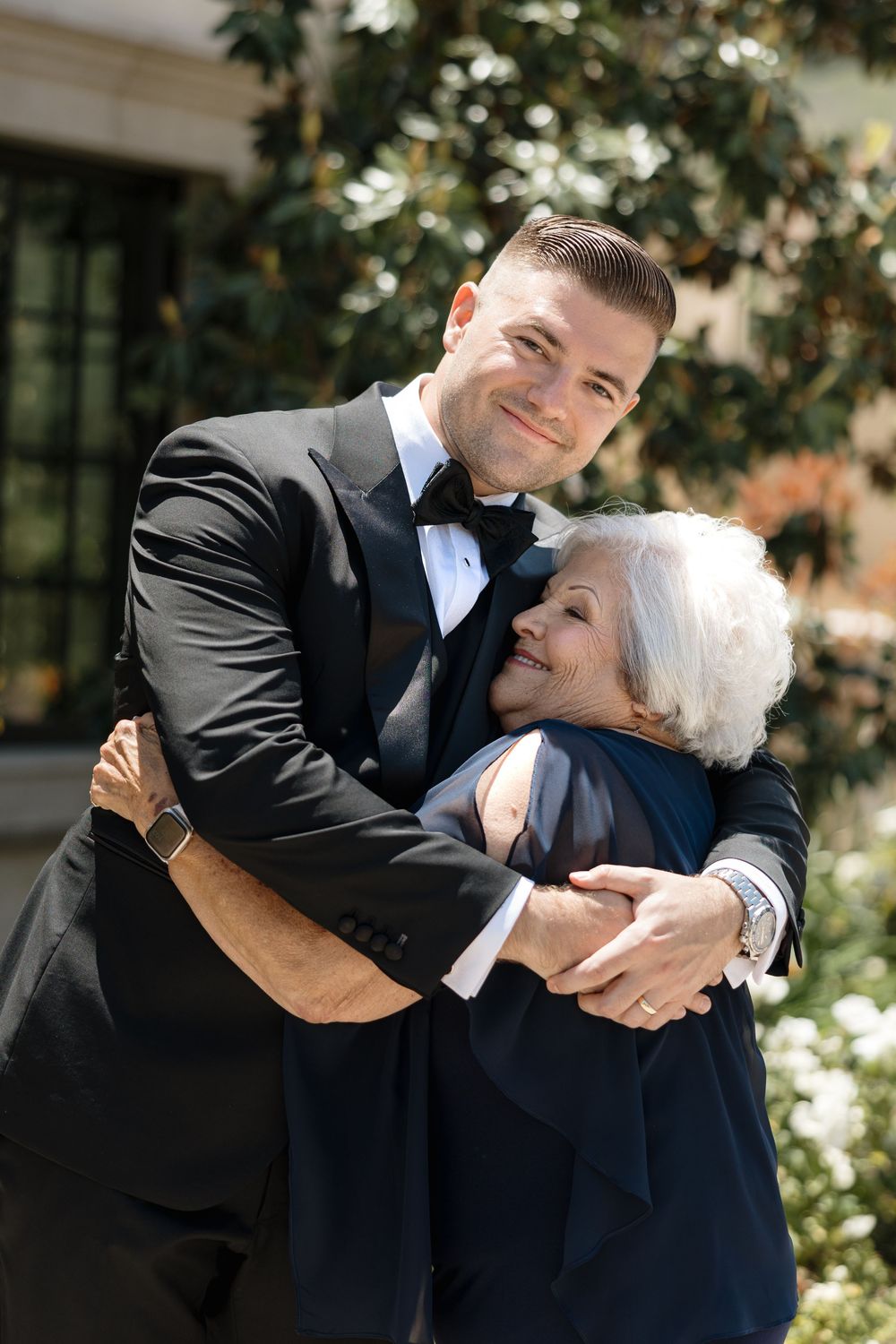 Two people in formal attire embrace and dance together during a special outdoor event.