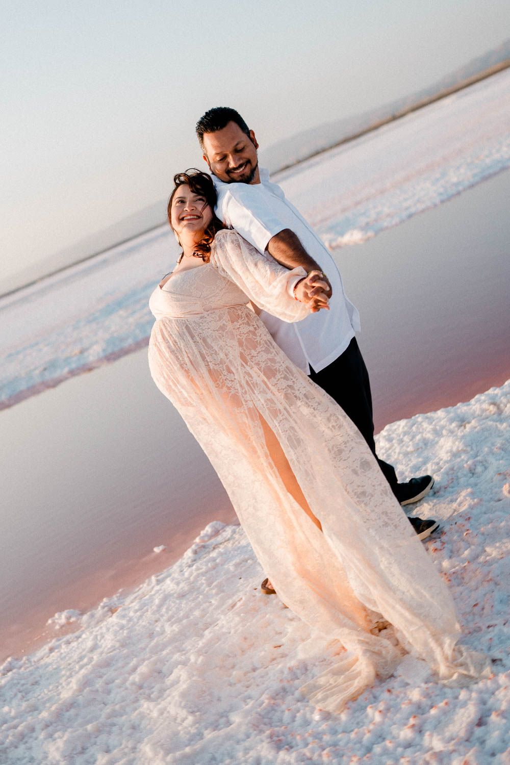 A couple dances on snow-covered ground at sunset, with the person in white being dipped in an elegant dance move.