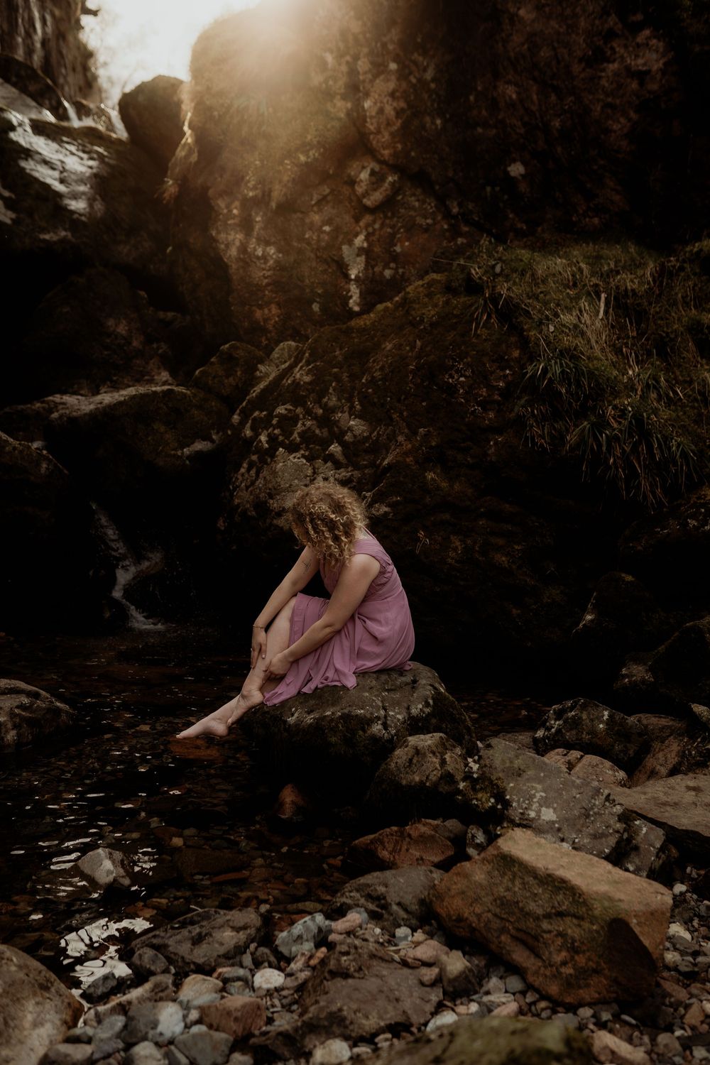 Desirée in een roze jurk bij een waterval in Glencoe bij de Three Sisters, Schotland