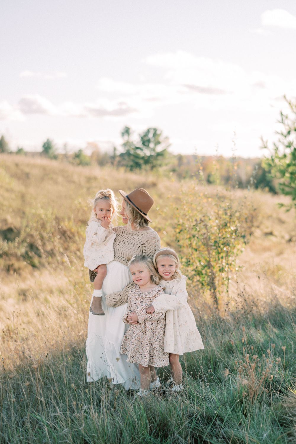 Family portrait in autumn field with coordinating white and beige outfits.